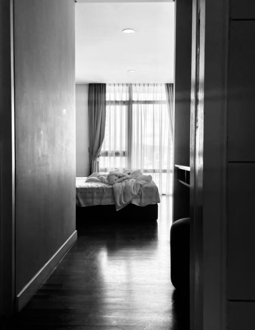 A quiet bedroom seen from the hallway of a lived-in home, door open