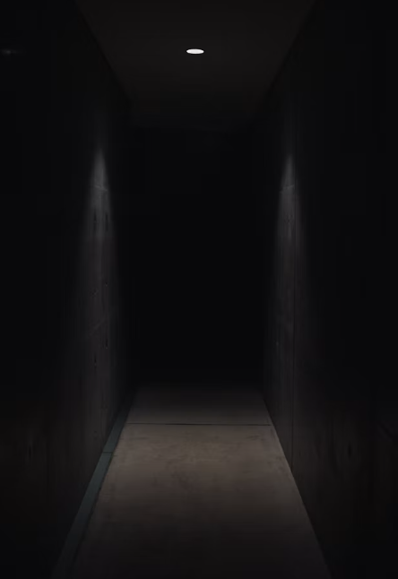 A dark hallway at night with one low light near the floor
