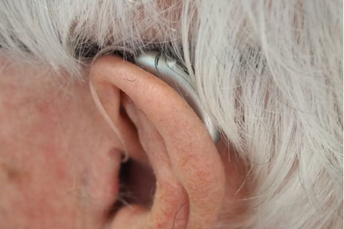 Close view of a behind-the-ear hearing aid worn by an older person