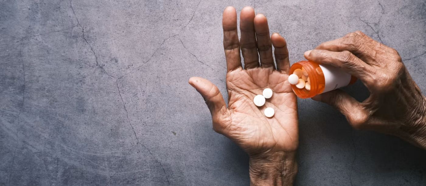 An older person tipping tablets from a prescription bottle into an open palm