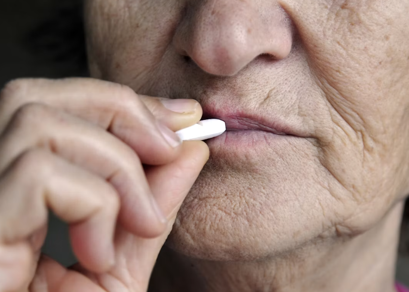 Close crop of an older woman taking a single tablet
