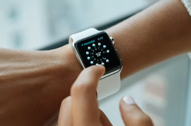A finger pressing the screen of a watch worn on the wrist